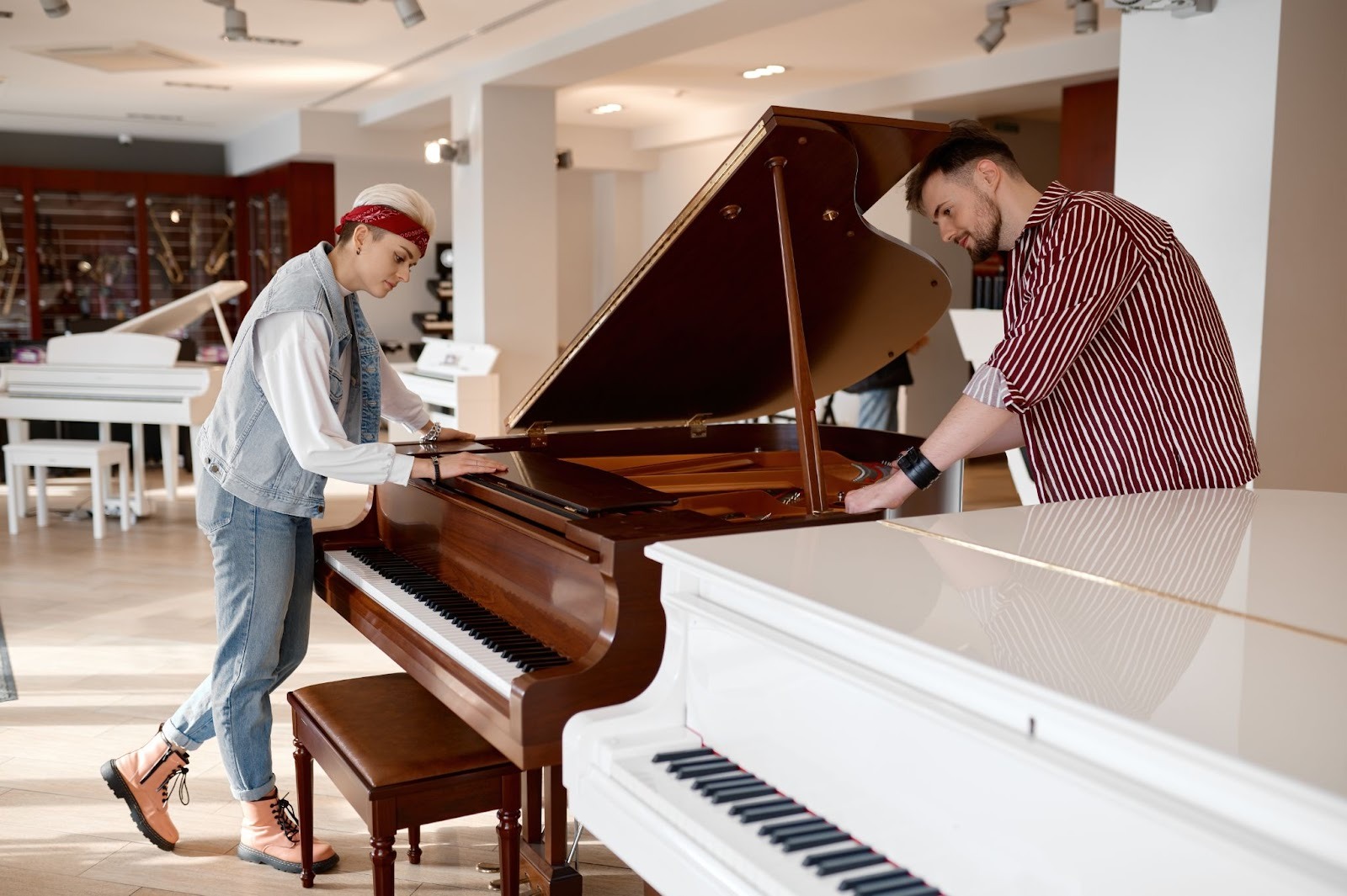 A young couple examines a brown piano.