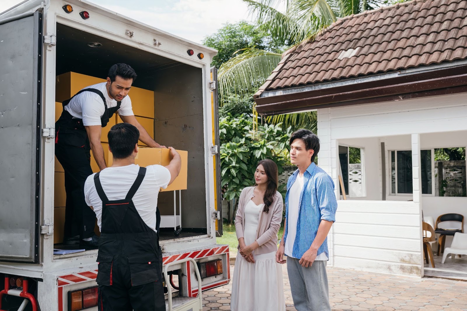 A team of movers packs a couple’s boxes into the back of a box truck.