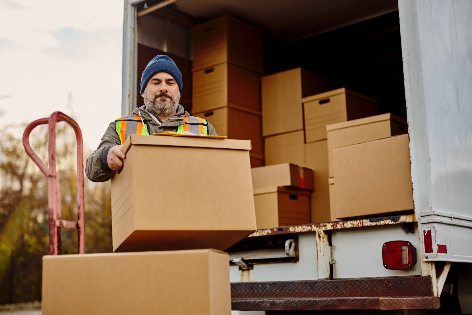 A male worker unloading moving boxes from a truck.